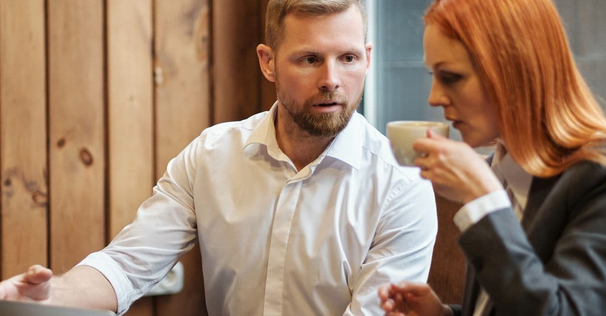 Ein Mann und eine Frau sitzen im Gespräch an einem Tisch; die Frau hält eine Tasse.